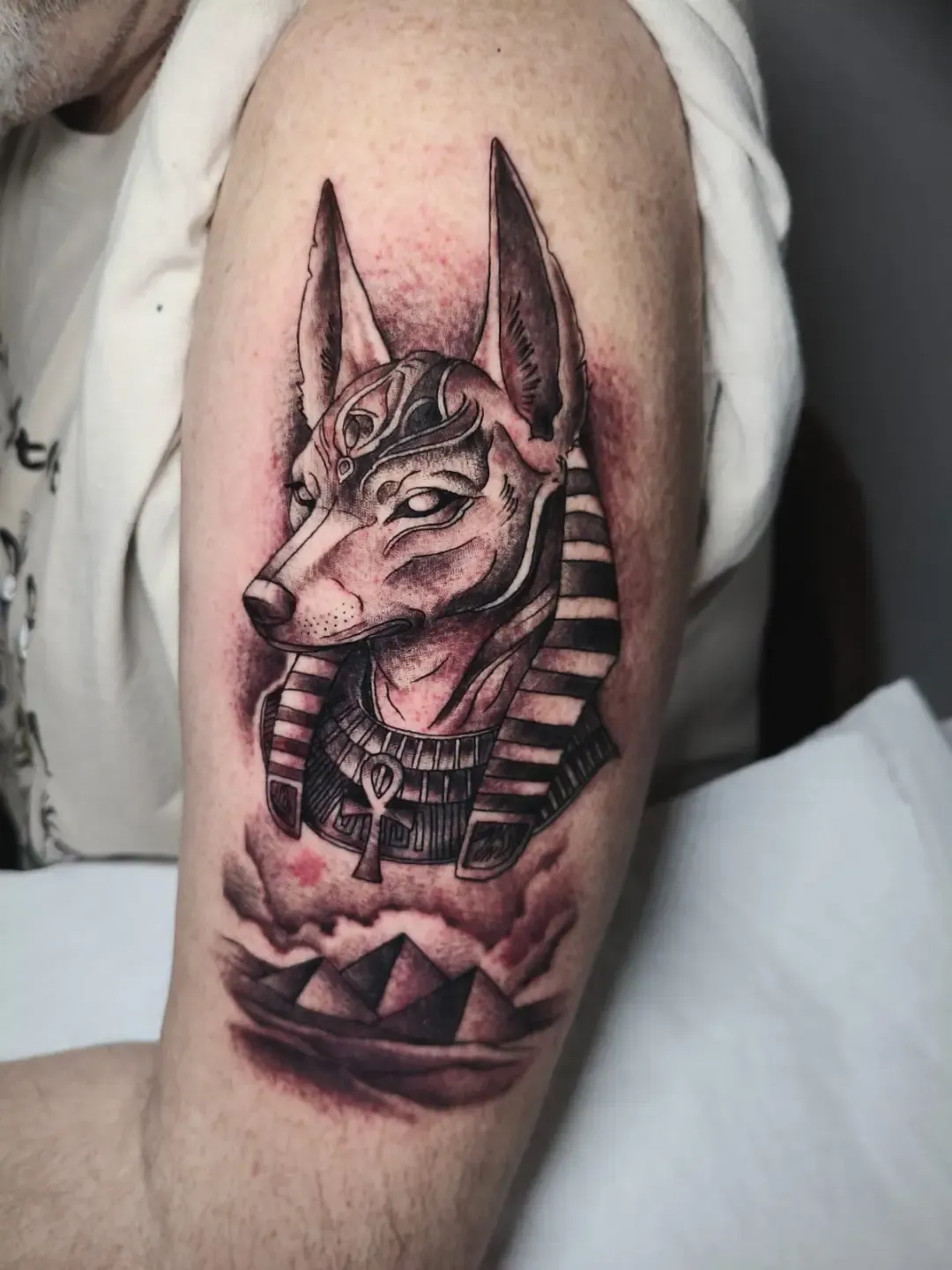Tatuaje black & grey de Anubis con pirámides en el brazo