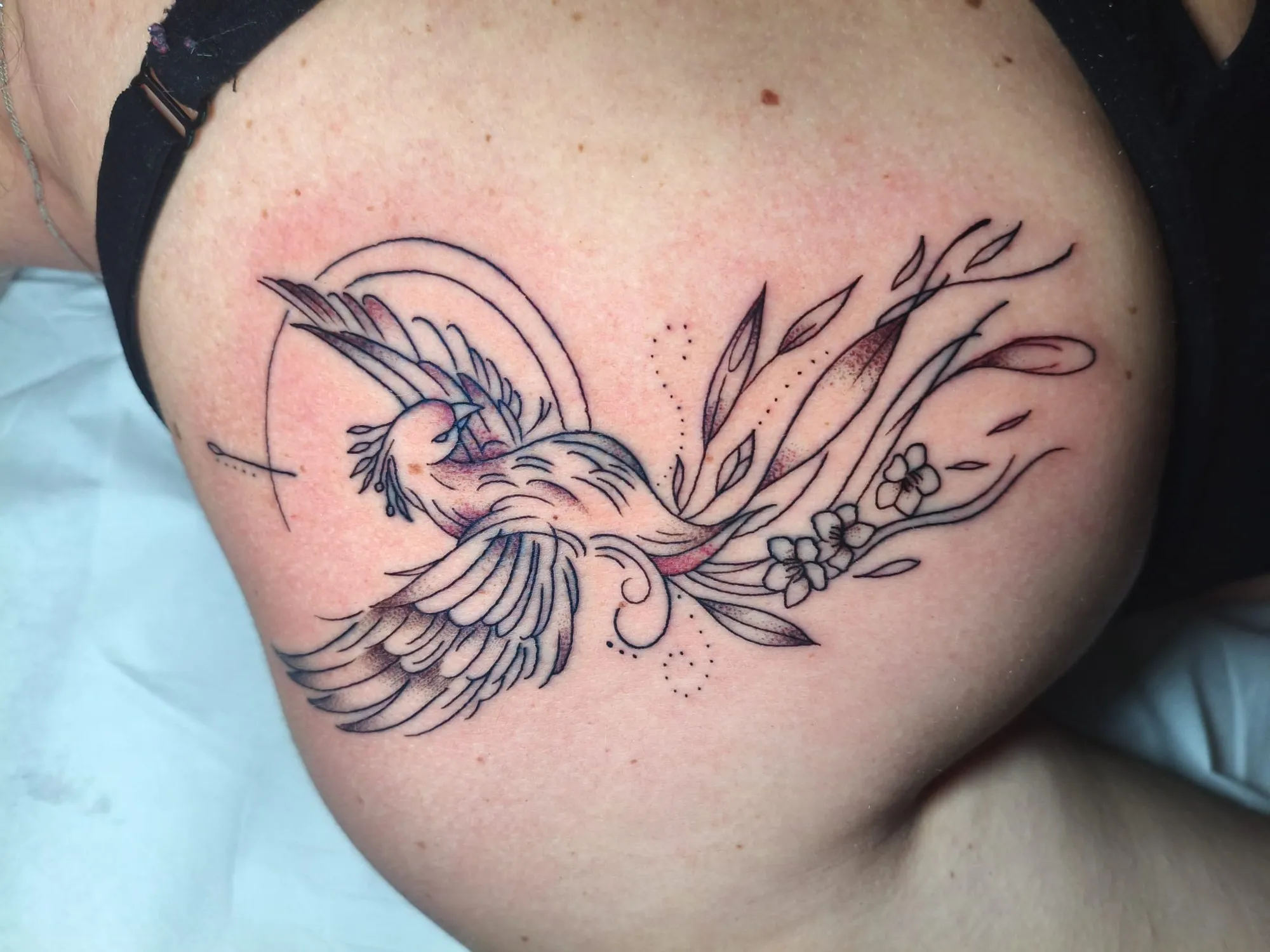 Tatuaje fine line de ave fénix con flores en el hombro