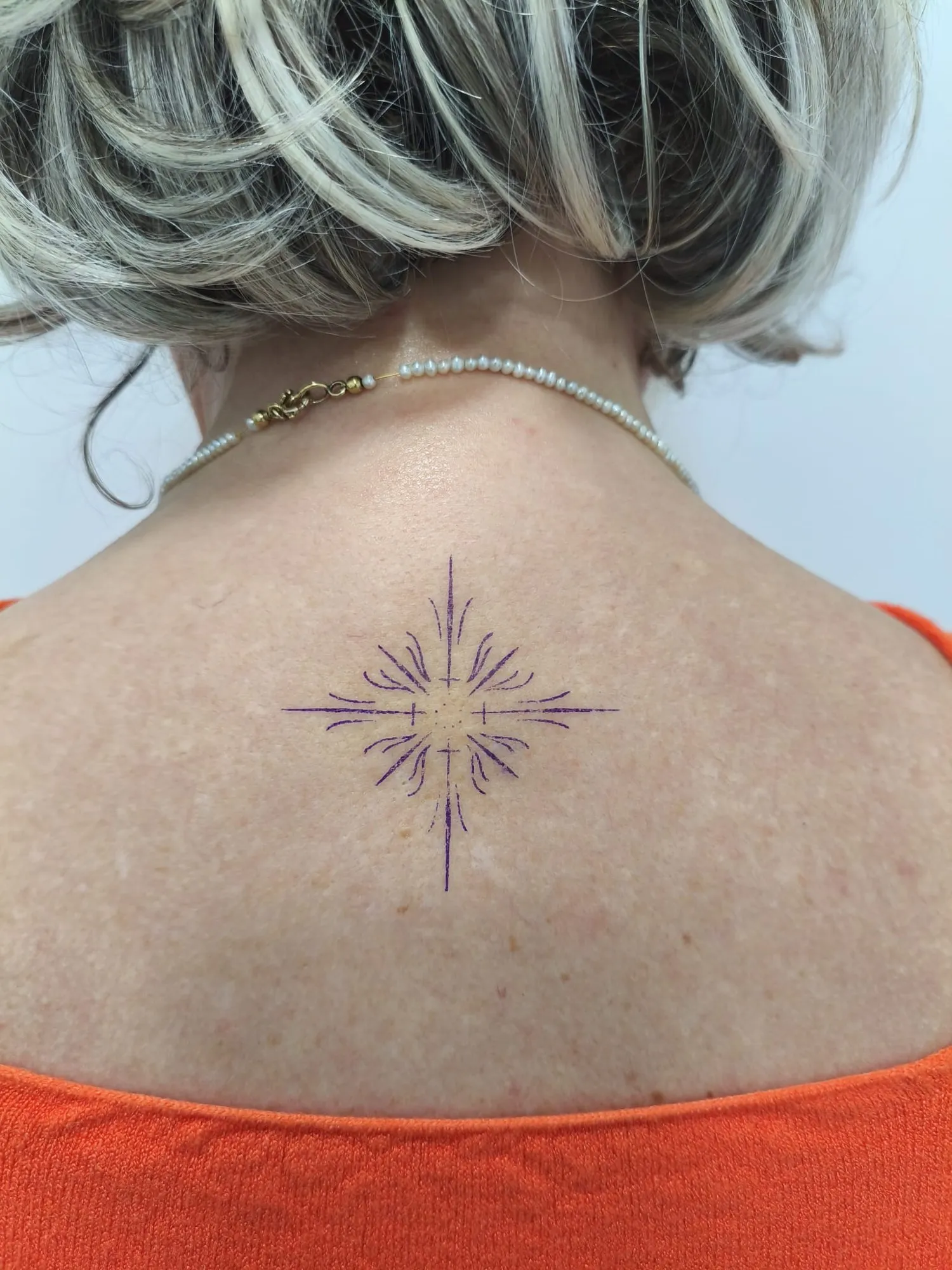 Tatuaje fine line de destello en la nuca