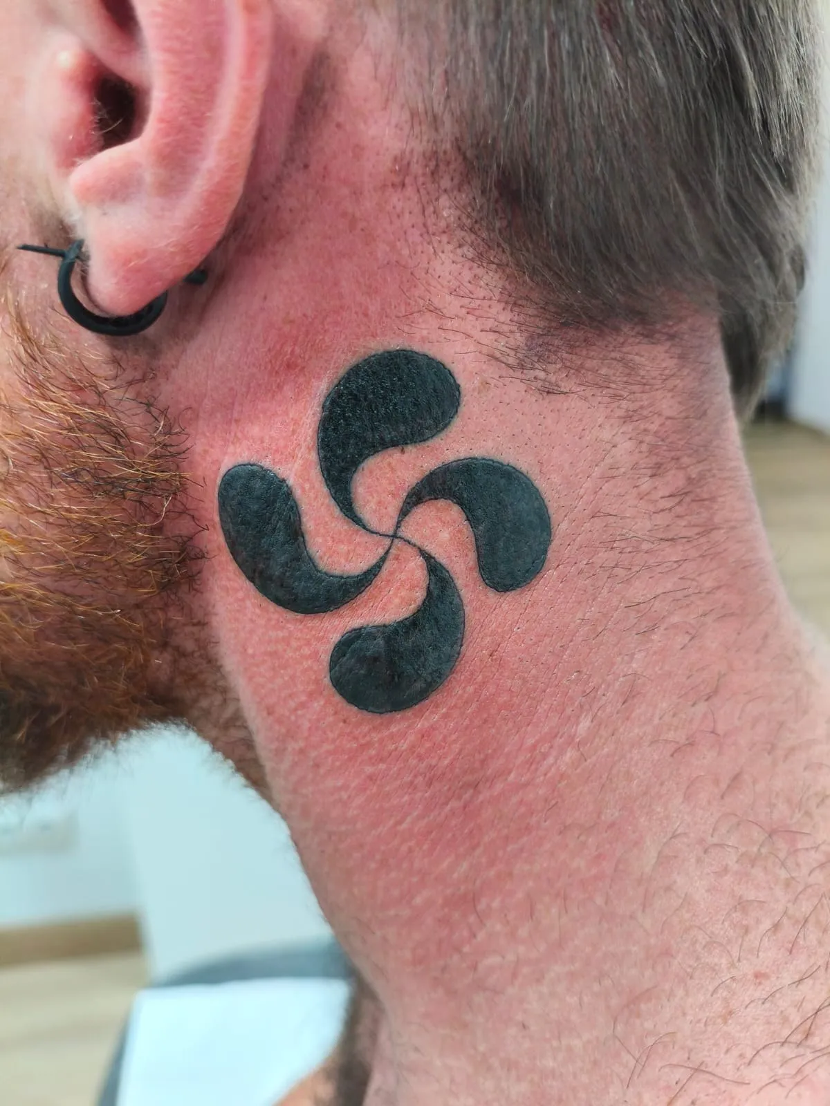Tatuaje blackwork de lauburu en el cuello