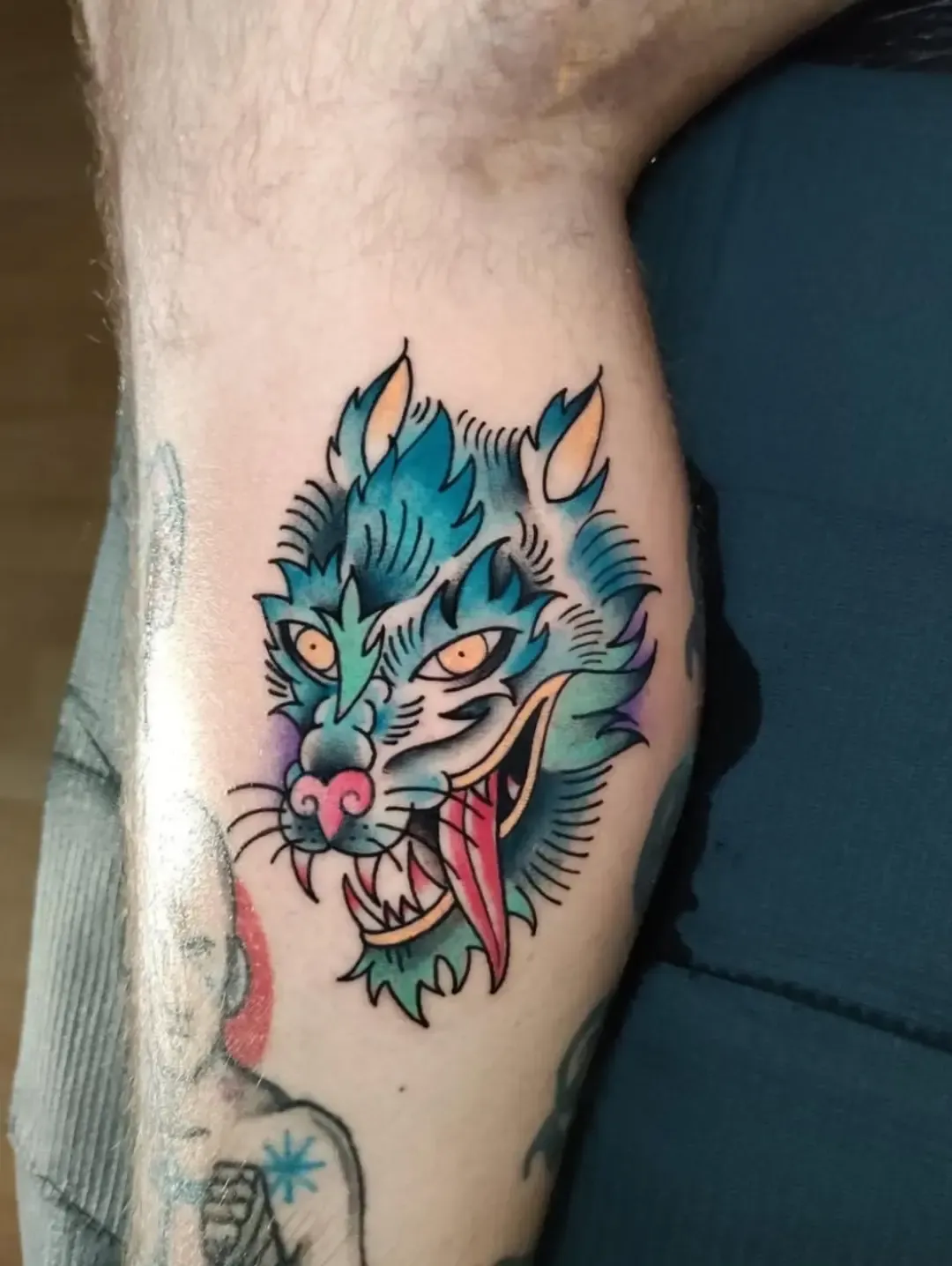 Tatuaje tradicional a color de lobo azul en el gemelo