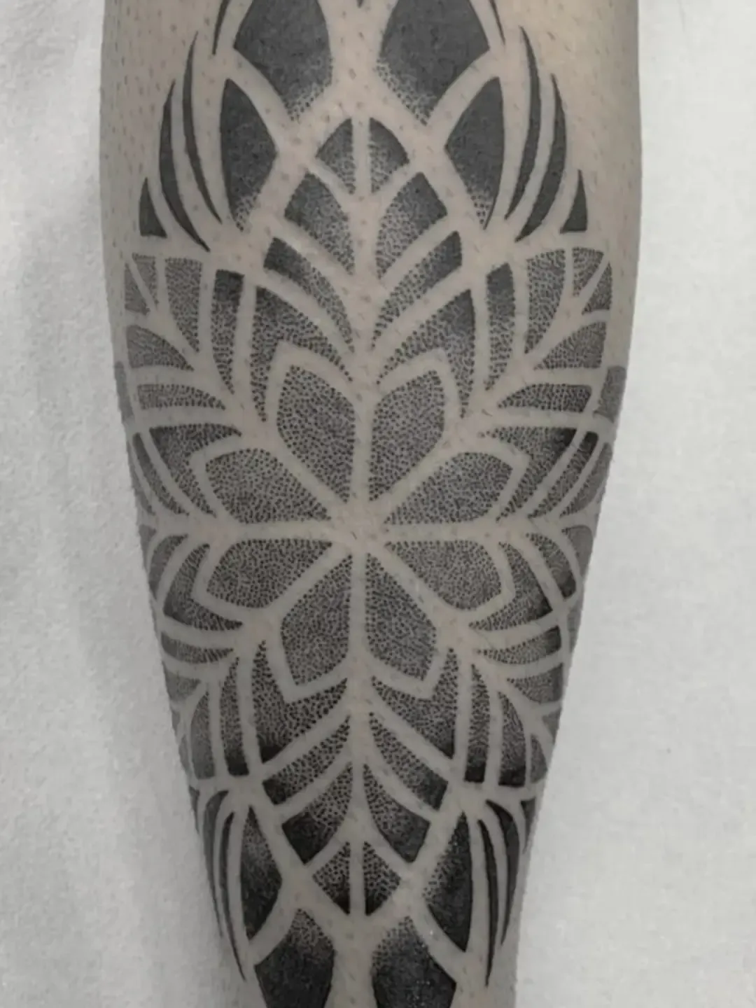Tatuaje geométrico dotwork de mandala en la pierna