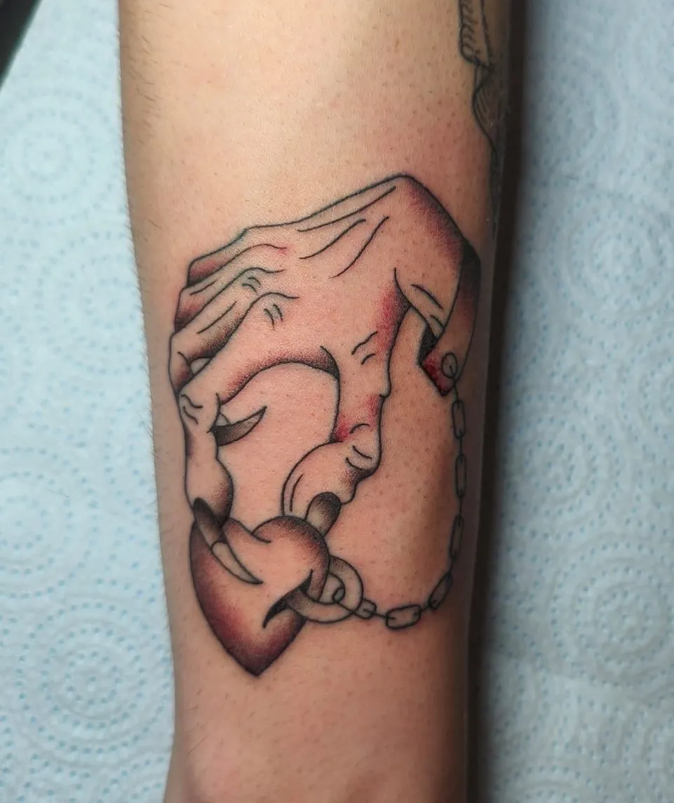 Tatuaje tradicional de manos con corazón candado y cadena