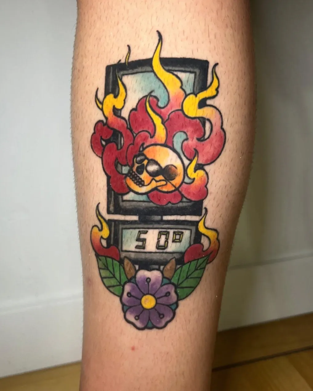 Tatuaje tradicional a color de parquímetro con calavera en llamas y flor