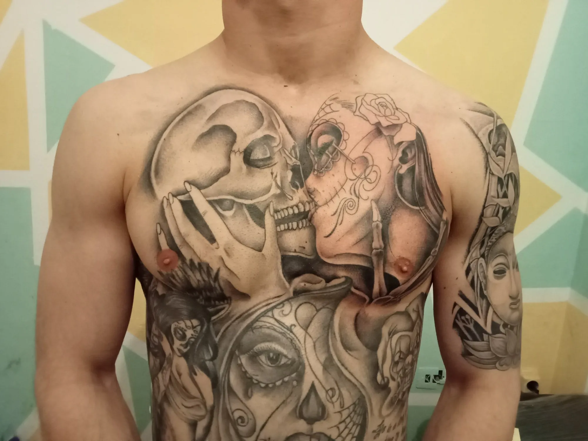 Tatuaje black & grey en el pecho de calavera y catrina besándose